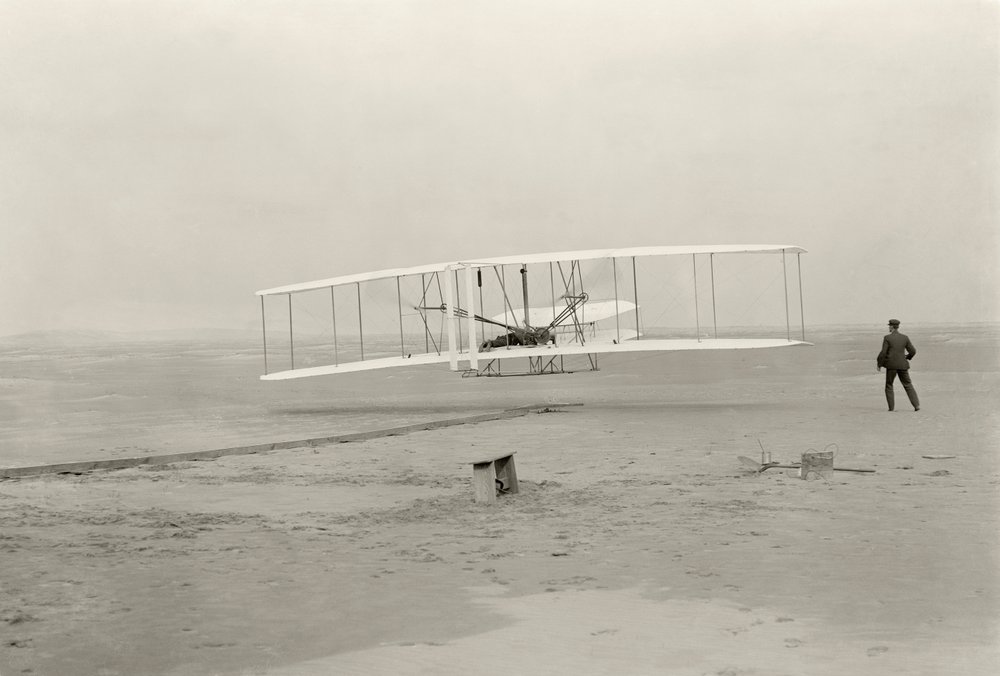 Der Wright Flyer I macht seinen ersten Flug von 120 Fuß in 12 Sekunden in Kitty Hawk, North Carolina von John T. Daniels