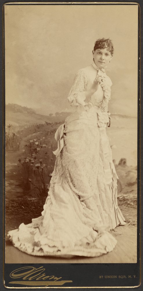 Unbekannte Frau in langem, elegantem weißen Kleid, stehend von Napoleon Sarony