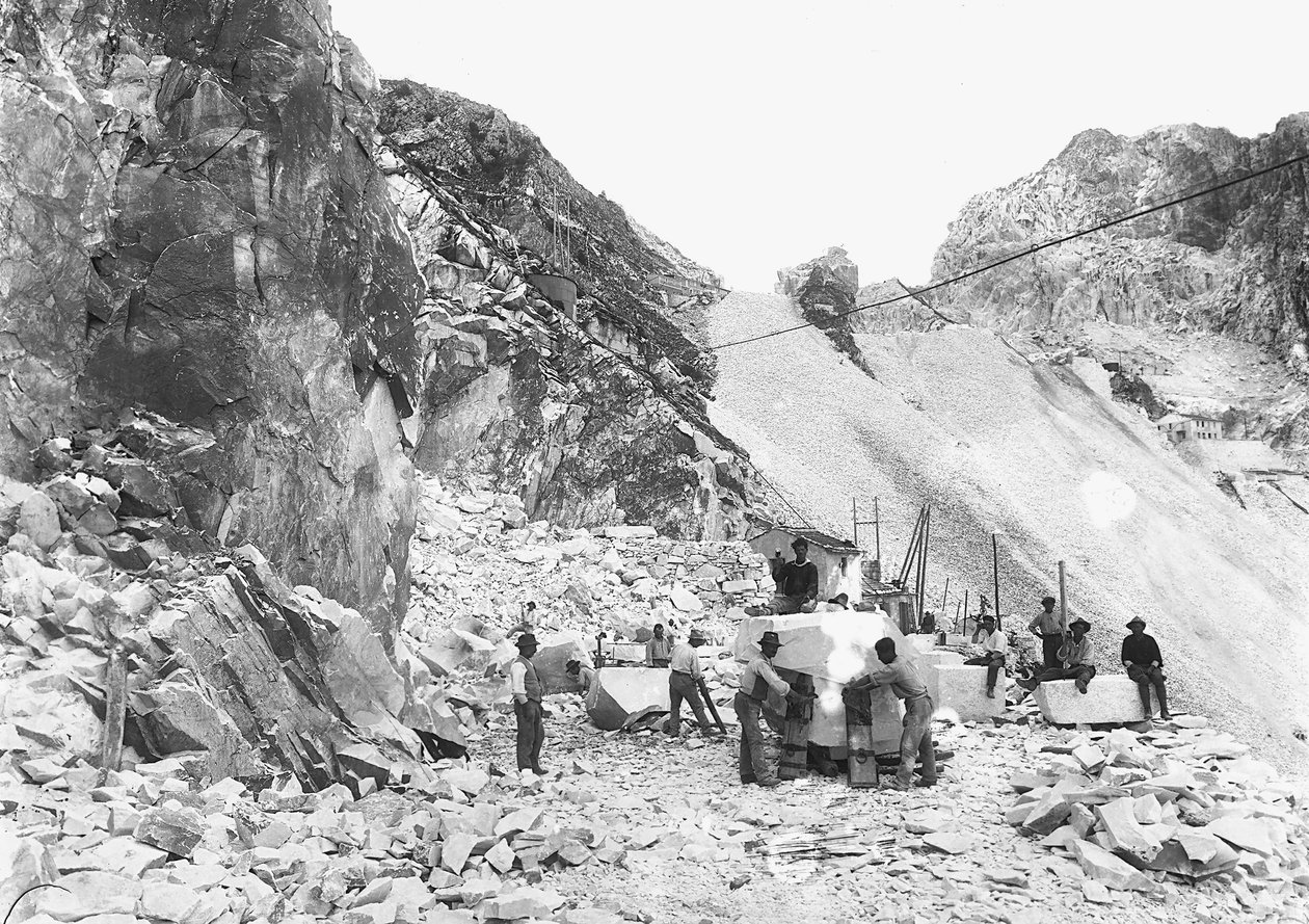 Ausgräber bei der Arbeit in einem Marmorbruch in den Apuanischen Alpen, Toskana. Einige von ihnen sitzen auf bereits quadratischen Marmorblöcken. von A. Corsini