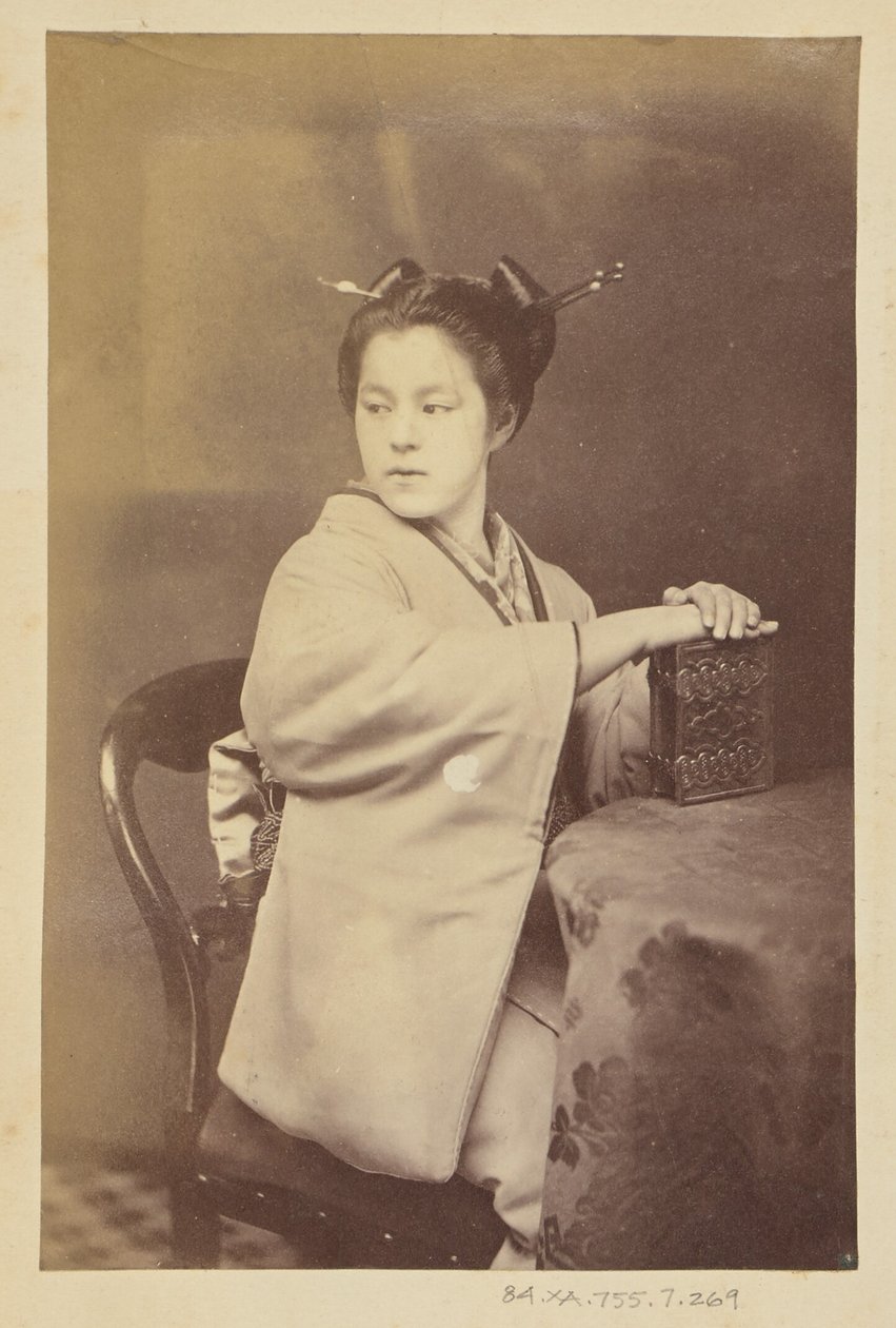 Sitzende japanische Frau mit einem Cartes-de-Visite-Album an einem Tisch von Felice Beato