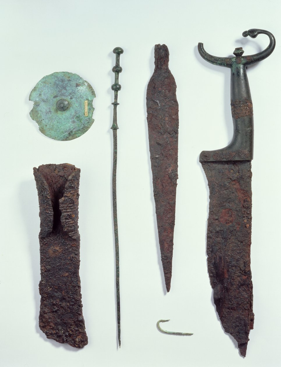 Von oben nach unten: Messer, Speerspitze, Angelhaken, Wäscheklammer, Gürtelplatte und Axt, alle gefunden in Männergräbern in Hallstatt, Eisenzeit von Iron Age