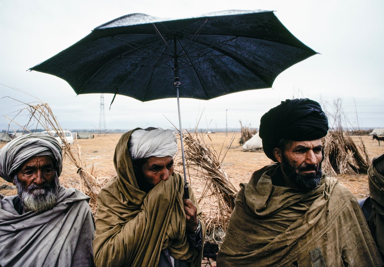 Pakistanische Männer mit einem Regenschirm und traditionellen Gewändern von James L Stanfield