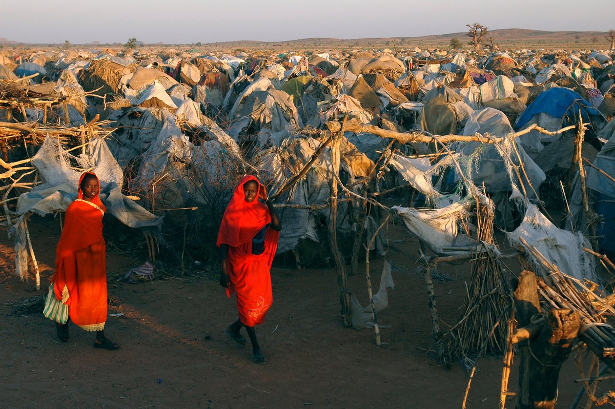 In leuchtend roten Kleidern gekleidet, gehen Frauen durch das Otash-Lager für Binnenvertriebene von Unbekannt Unbekannt