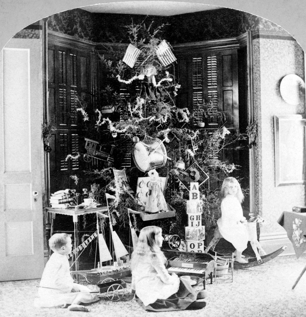 Kinder versammeln sich am Fuße des Baumes, umgeben von Geschenken am Weihnachtsmorgen. von Unknown photographer