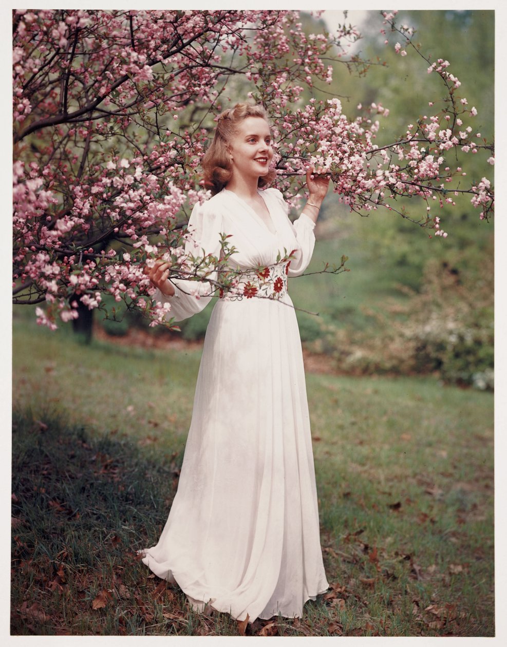 Frau, die ein Kleid in der Nähe von Blüten modelliert, ca. 1940er von Frederick (attr. to) Barnard