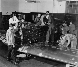 Soldatenschüler arbeiten an einem "Flying Patch," einem Curtiss "Warhawk"-Jagdflugzeug ohne Motor oder Heckbaugruppe, mit simulierten Einschusslöchern und Flicken, ca. 1942