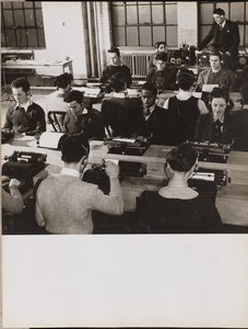 Menschen sitzen vor Schreibmaschinen und tragen Kopfhörer