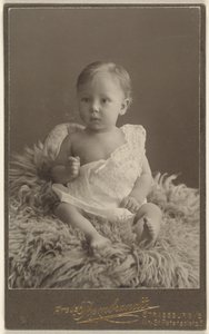 Unidentifiziertes Baby auf einem Lammfell-Teppich sitzend