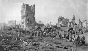 Eine unbekannte australische Maschinengewehrabteilung mit Packpferden passiert die Ruinen der Tuchhalle. Beachten Sie die im Hintergrund geparkten Lastwagen, 19. Oktober 1917 von Australian Photographer
