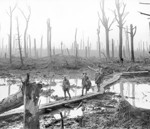 Fünf Australier, Mitglieder einer Feldartilleriebrigade, passieren einen Duckboard-Weg über Schlamm und Wasser zwischen kahlen Baumstämmen im verwüsteten Chateau Wood, einem Teil eines der Schlachtfelder von Australian Photographer
