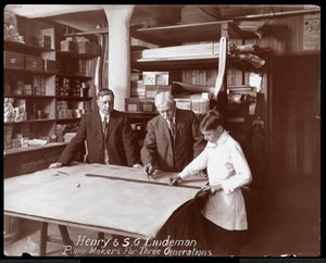 Porträt von Henry und S.G. Lindeman mit ihrem Sohn oder Enkel, der über Zeichnungen für ein Klavier steht, 1910