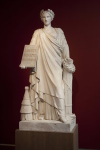 Die Französische Republik. Dargestellt als Frau in antiker Drapierung und mit einer Tafel mit dem Motto „Liberté, Égalité, Fraternité“, der Bienenstock zu ihren Füßen symbolisiert Fruchtbarkeit und Ordnung, die Axt und der Balken sind Machtinsignien, diese von Ferdinand Taluet
