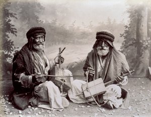 Porträt von zwei arabischen Musikern in bescheidener ethnischer Kleidung. Die älteren Männer posieren im Studio, auf dem Boden sitzend. Hinter ihnen ist ein Hintergrund mit einer bewaldeten Landschaft von Félix Bonfils