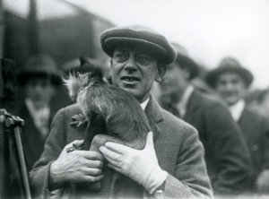 Ein Schwarzhauben-Mangabe, möglicherweise Freckles, mit seinem Betreuer, nimmt an einer Außenübertragung aus dem London Zoo teil, 1925 von Frederick William Bond