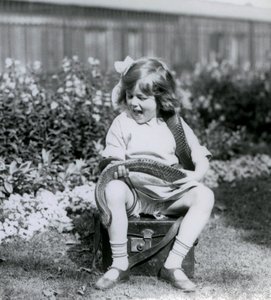 Ein junges Mädchen, Betty, hält eine östliche Indigo-Schlange, während sie auf einem Lederkoffer sitzt, Londoner Zoo, 1924