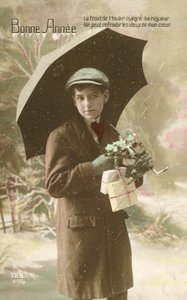 Hübscher, gut gekleideter Junge, der im Schnee mit einem Regenschirm steht