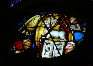 Das Westrosenfenster zeigt eine Szene aus dem Buch der Offenbarung: Lamm mit sieben Hörnern und sieben Augen öffnet das Buch. Beachten Sie die Symbole der vier Evangelisten (5:7).