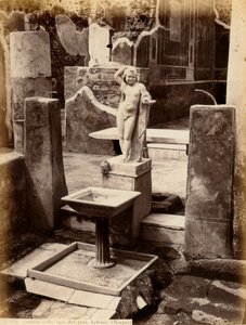 Ein Brunnen, bestehend aus einer Skulptur eines nackten Jungen. Der Brunnen befindet sich im Haus des Balcone pensile in Pompeji