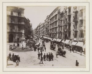 Ansicht der Via Roma in Neapel mit einer Statue, Geschäften, Pferdekutschen und Passanten