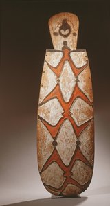 Ovaler Asmat-Schild, geschnitzt mit stilisierten Figuren, eine Maske oben