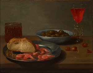 Ein Teller mit Garnelen und einem Brötchen, eine Schale mit Oliven, ein Façon de Venise, ein Glas Bier und Mandeln auf einem Tisch