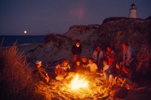 Freunde versammeln sich um ein Sommerlagerfeuer am Great Point Leuchtturm. Nantucket Island