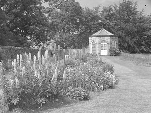Gartenhaus oder Folly im Garten mit Rasen und Blumenbeeten