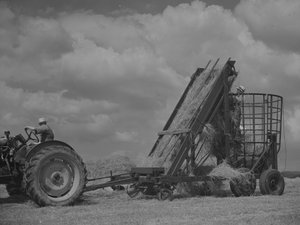Traktor zieht mobilen Rahmen und Heu wird hineingeladen