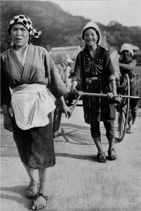Drei Generationen von Frauen bewegen einen Wagen mit Großmutter hinten, schiebend, ca. 1900, 1921
