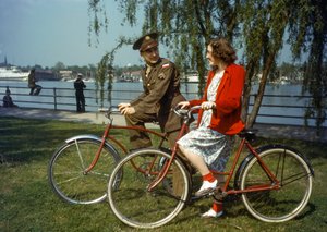 Sitzend auf Fahrrädern in der Nähe eines Hafens, US-Armeeoffizier flirtet mit einer jungen Frau auf Trinidad von Luis Marden