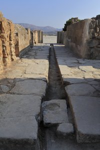 Minoische archäologische Stätte von Phaistos. Breiter Korridor mit einem Entwässerungskanal hinter dem Torflügel des Nordflügels, der sich vom zentralen Hof öffnet und zu einem inneren Hof neben den Königlichen Gemächern führt. Phaistos, Kreta. von Minoan