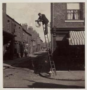 Mann reinigt eine Gaslaterne, um 1905