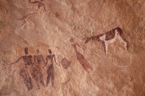 Felskunst, Vorgeschichte: Felsmalerei einer Gruppe von Figuren und einer zweifarbigen Kuh mit großen Hörnern in einem verzierten Schutzraum im Uweinat-Massiv, Ägypten. (Zeitraum von 8000 bis 3000 v. Chr.). Fotografie von Unbekannt