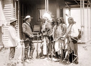 Drei Cheyenne in zeremoniellen Kostümen und mit Gewehren begrüßen einen Weißen, begleitet von einem Dolmetscher. Spätes 19. Jahrhundert