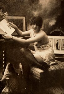 Porträt einer jungen Frau in intimer Kleidung, die an einem Tisch mit einem Buch sitzt von Unknown photographer