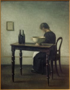 Frau, hinter einem Tisch sitzend