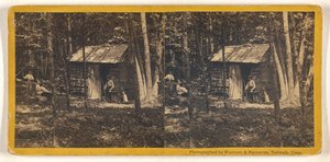 Familie vor ihrer Blockhütte im Wald
