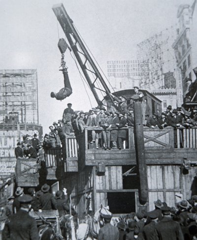 Houdini entkommt aus einer Zwangsjacke, während er an einem Kran in New York City hängt von American Photographer