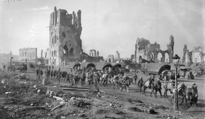 Eine unbekannte australische Maschinengewehrabteilung mit Packpferden passiert die Ruinen der Tuchhalle. Beachten Sie die im Hintergrund geparkten Lastwagen, 19. Oktober 1917 von Australian Photographer