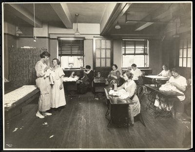 Blinde junge Frauen und eine Lehrerin beim Nähen in einem Klassenzimmer der New York Association for the Blind, 111 East 59th Street, New York, 1921 von Byron Company