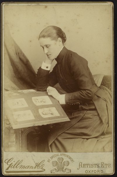 Figur einer sitzenden Frau, die ein Fotoalbum inspiziert von English Photographer