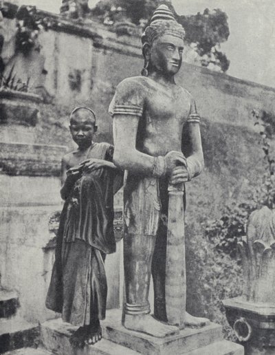 Junger buddhistischer Novizenmönch neben einer Buddha-Statue, Französisch-Indochina (s/w Foto) von Ewing Galloway