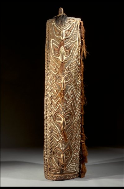 Gebogener rechteckiger Sepik-Schild, Vorderseite mit zentralem Band von fünf Masken, jede mit Faser im durchbohrten Septum, innerhalb eines geschnitzten Zickzackmusters von Guinean New