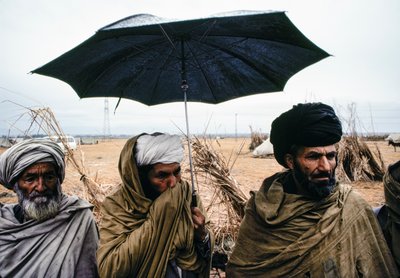 Pakistanische Männer mit einem Regenschirm und traditionellen Gewändern von James L Stanfield