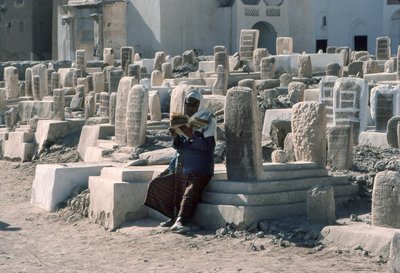 Ein jemenitischer Mann rezitiert den Koran auf einem Friedhof mit Gräbern in Sayun, Hadramaut, Südjemen. von Lynn Abercrombie
