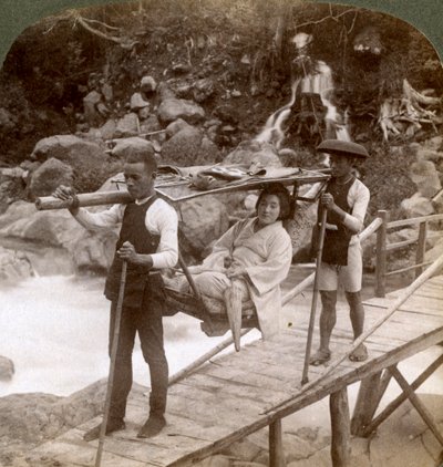 Japanische Frau in einem Yamakago-Bergstuhl überquert den reißenden Daiya-Fluss in der Nähe von Nikko, Japan von Underwood and Underwood