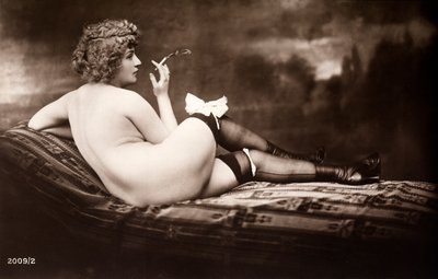 Porträt einer jungen Frau, die nackt posiert, mit dem Rücken zugewandt, während sie eine Zigarette raucht von Unknown photographer
