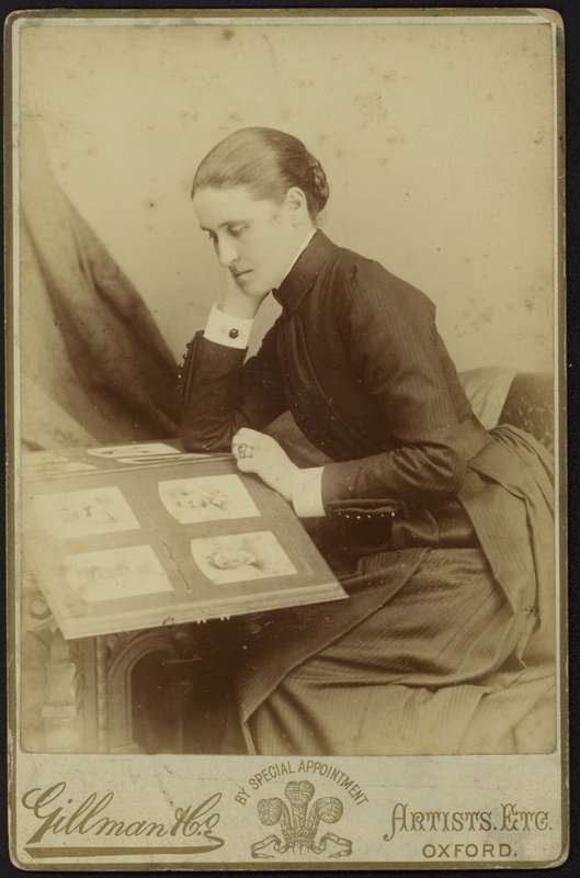 Figur einer sitzenden Frau, die ein Fotoalbum inspiziert von English Photographer
