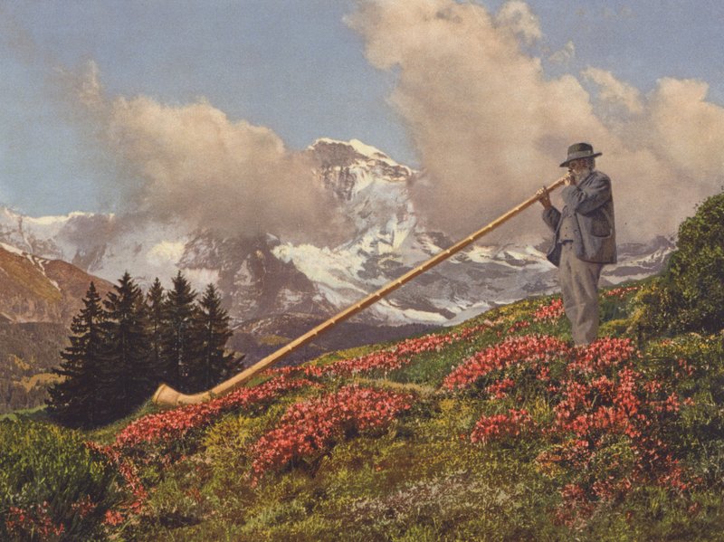 Schweiz: Ein Alphornbläser, die Jungfrau im Hintergrund von Jean Gaberell