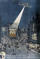 Alkoholwerbung „White Rock“: Ein Flugzeug beleuchtet das „White Rock“-Plakat an einem Gebäude am Times Square in New York. 1912.